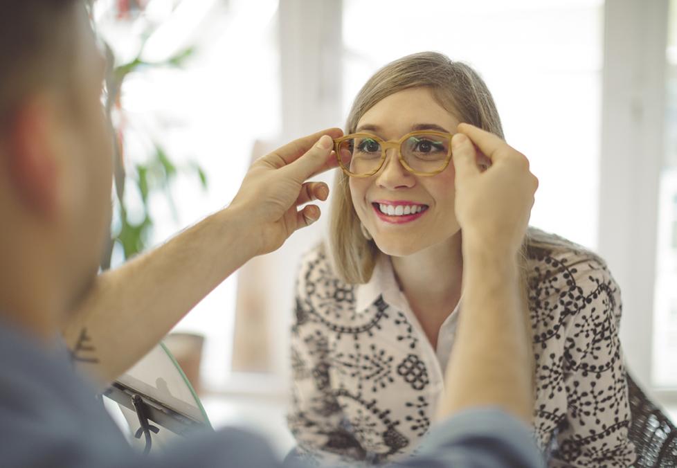 A young woman trying on glasses at a store