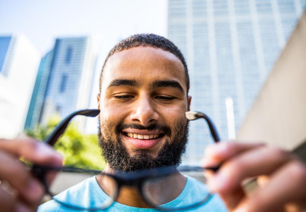 Young man putting on glasses