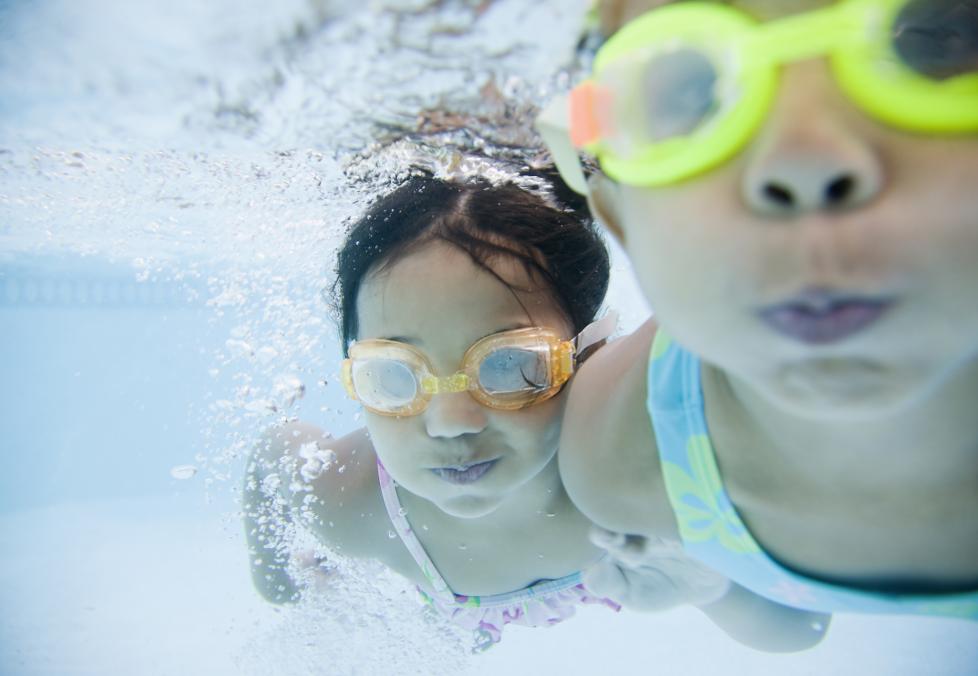 two girls swimming wearing googles