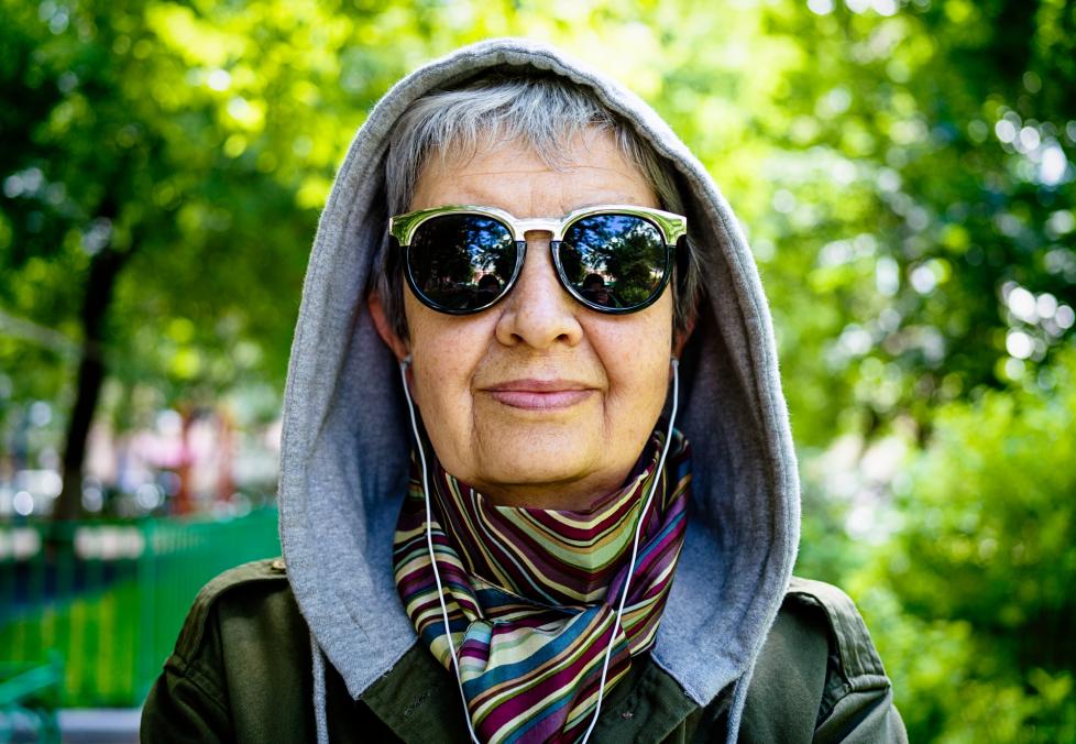 Woman in park wearing sunglasses.