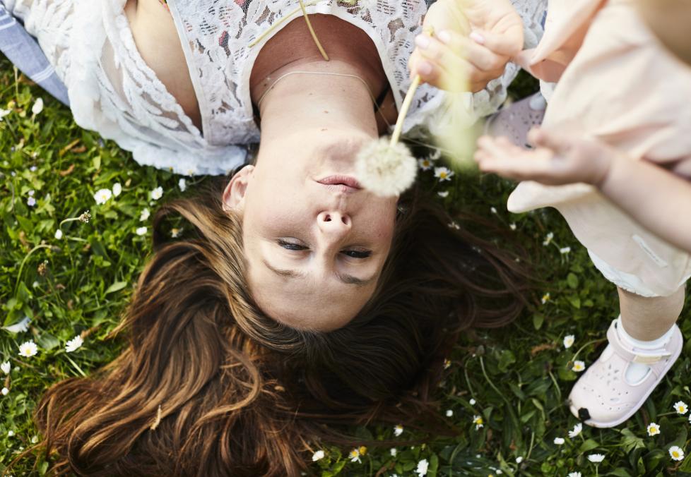 Allergy season is here and your eyes know it. Your America's Best optometrist can help you find relief. Woman in grass blowing a dandelion.