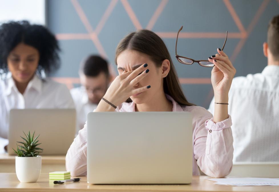 A young woman experiencing eye strain at her computer