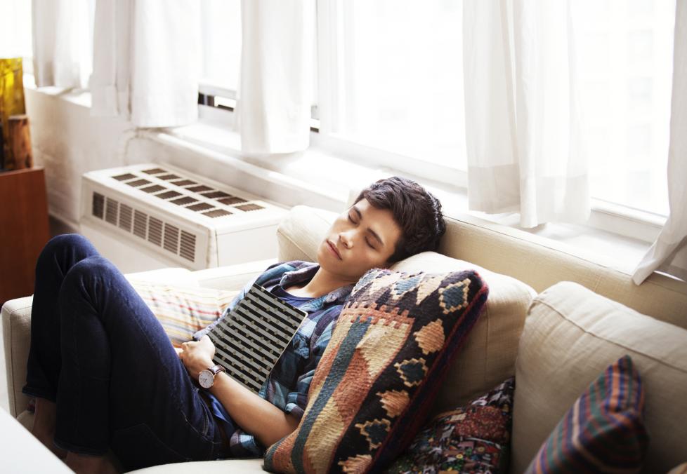 Young man napping on couch wearing contact lenses.