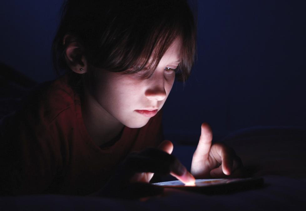 Young girl using her smartphone in the dark.