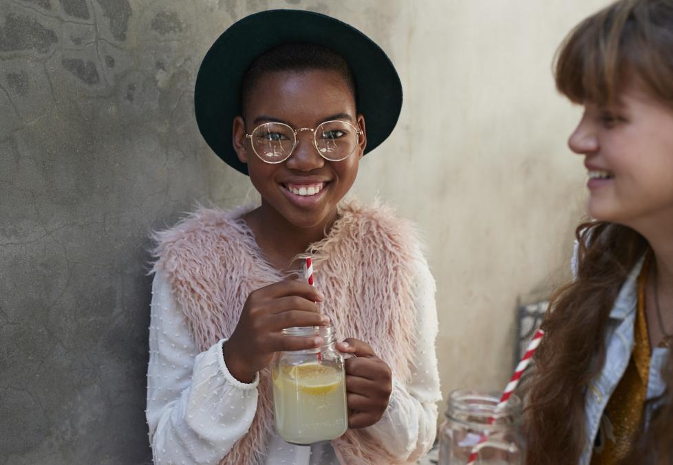 Preteen girl wearing glasses holding lemonade.