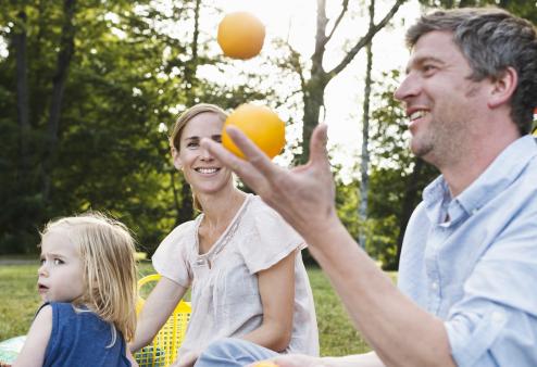 Dad juggling in park with his family watching.