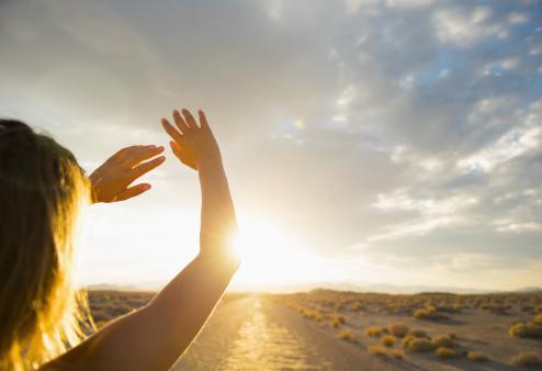 Woman looking at sun in the horizon.