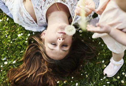 Allergy season is here and your eyes know it. Your America's Best optometrist can help you find relief. Woman in grass blowing a dandelion.