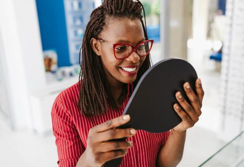 Happy young adult Black woman trying on glasses for a story on tips to find the best glasses for your face shape