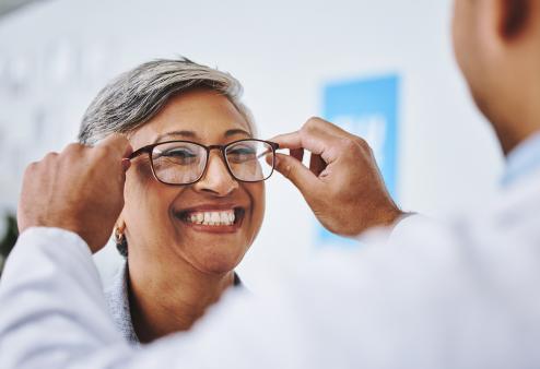 Happy older woman getting new glasses for a story on how biological age can affect your vision