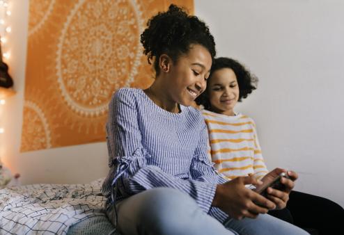 Two girl kids looking at a phone and smiling 