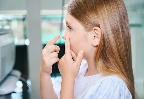 young girl putting in contact lenses for a story on MiSight contact lenses