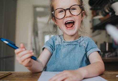 Smiling girl in glasses with pen in hand