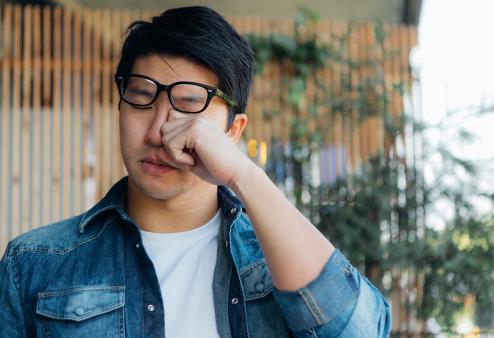 A man rubbing his eyes under his glasses