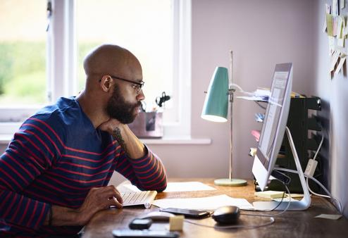 A man wearing glasses looking at his computer