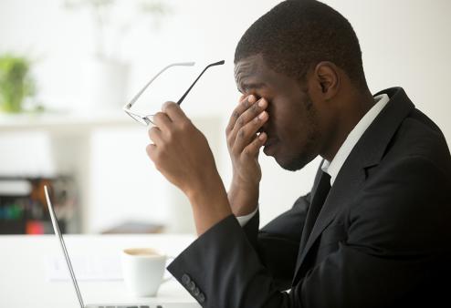 Business man with eye strain taking off glasses