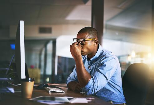 a man staring at his computer with a headache